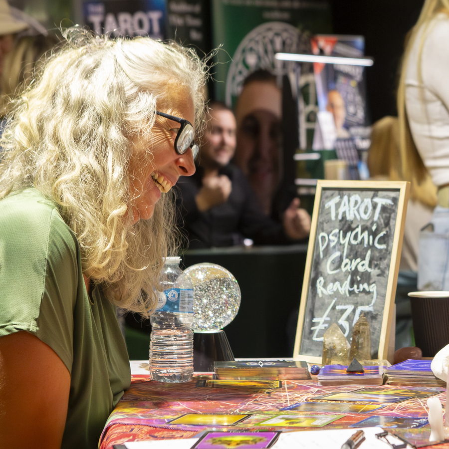 A tarot reader and visitor laughing across the reading table